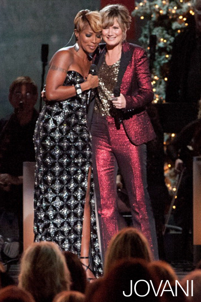 Model wearing Jovani 79121 black gown laughing alongside a person in red.