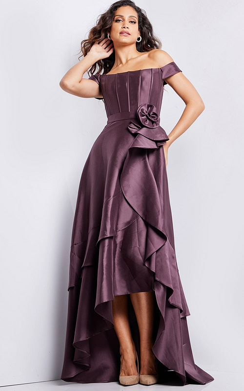 Model wearing Jovani 37014 brown dress with off-shoulder neckline and rosette detail at waist.