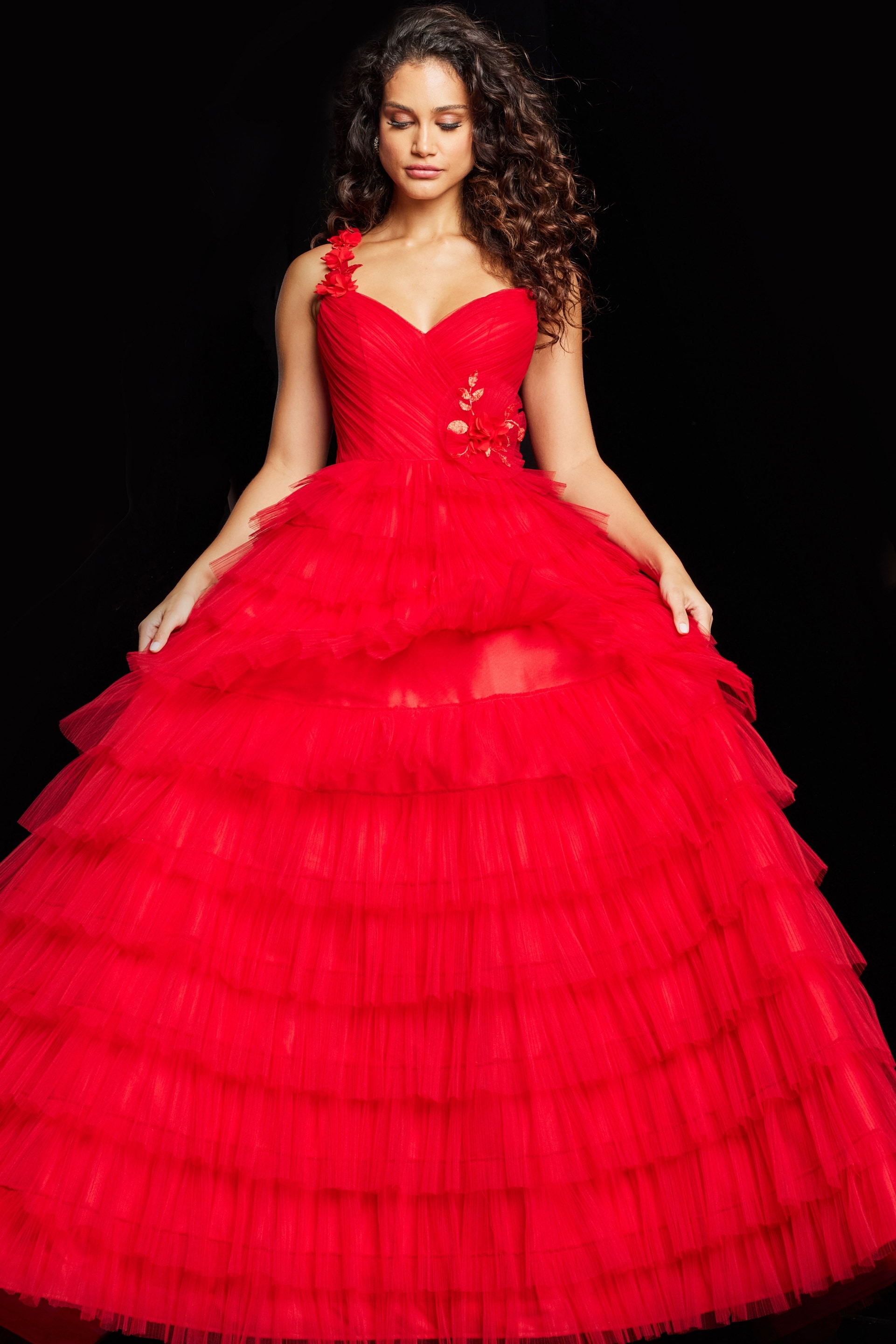 Model showcasing Jovani 37274 red dress's tiered skirt and floral shoulder appliqué.