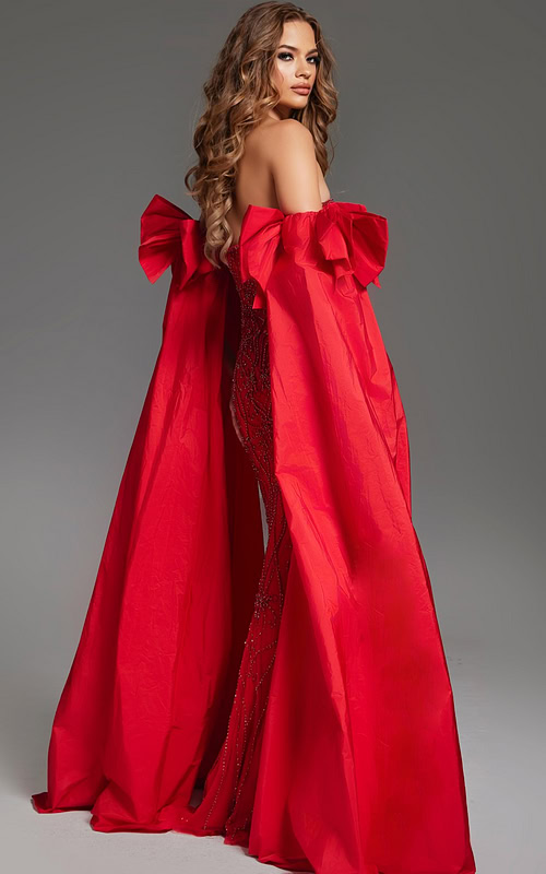 Model wearing Jovani 39377 back view showcasing flowing red cape and fitted gown silhouette.
