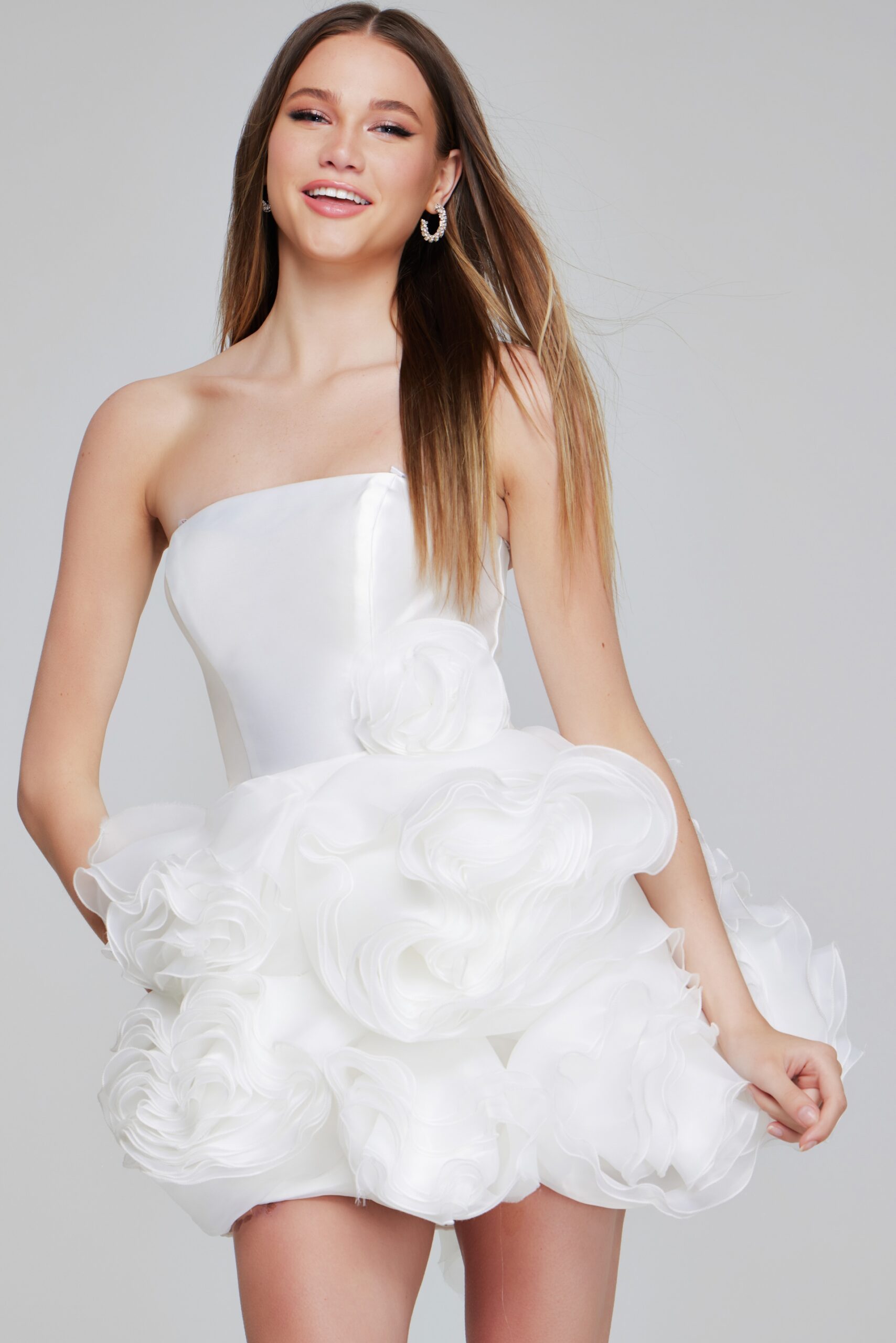 Model wearing Jovani 40334 white mini dress, showcasing floral appliquรฉs and a strapless neckline