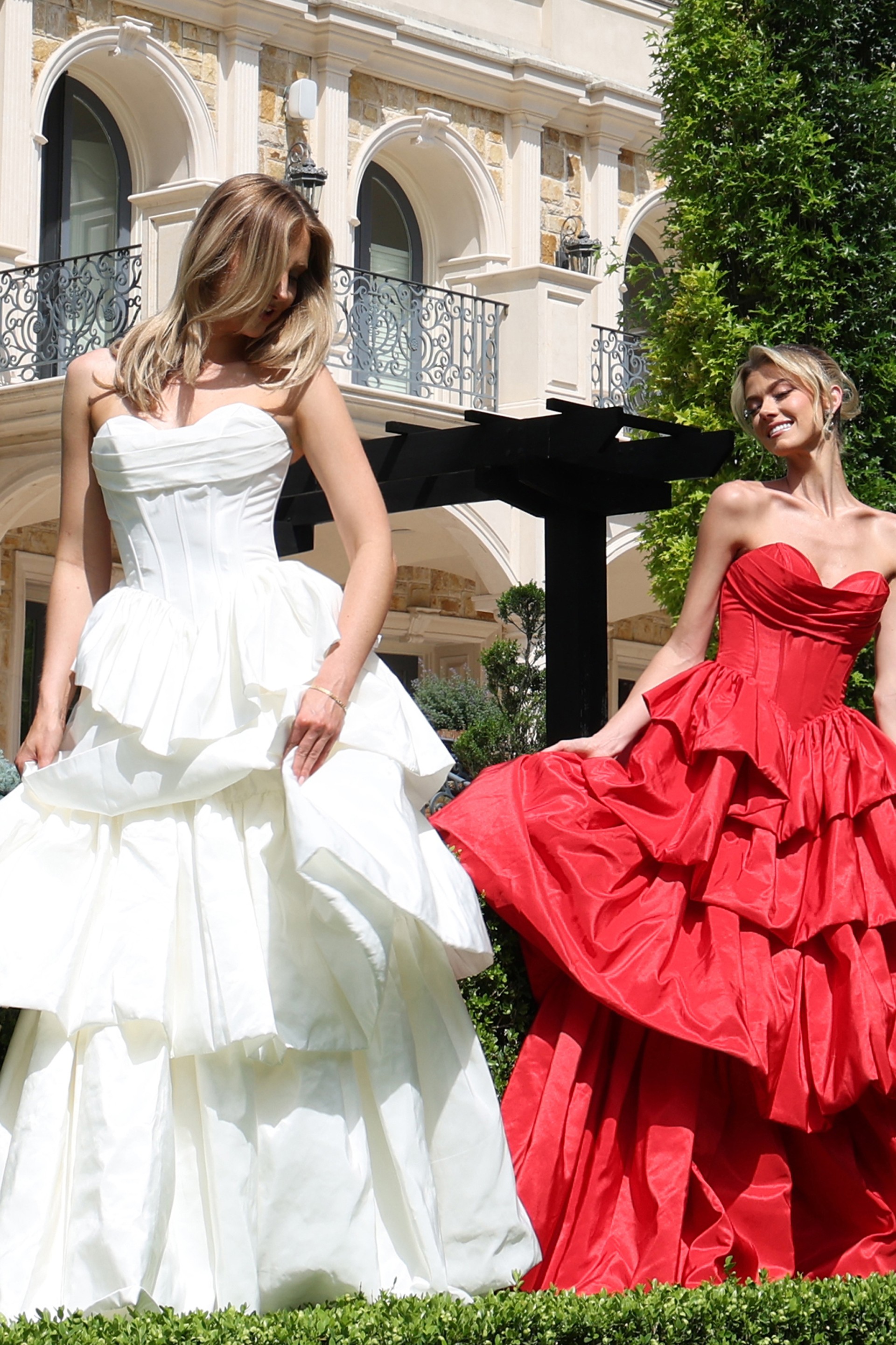strapless layered ruffle ball gown - two girls front, hair covering face smiling fanning skirt