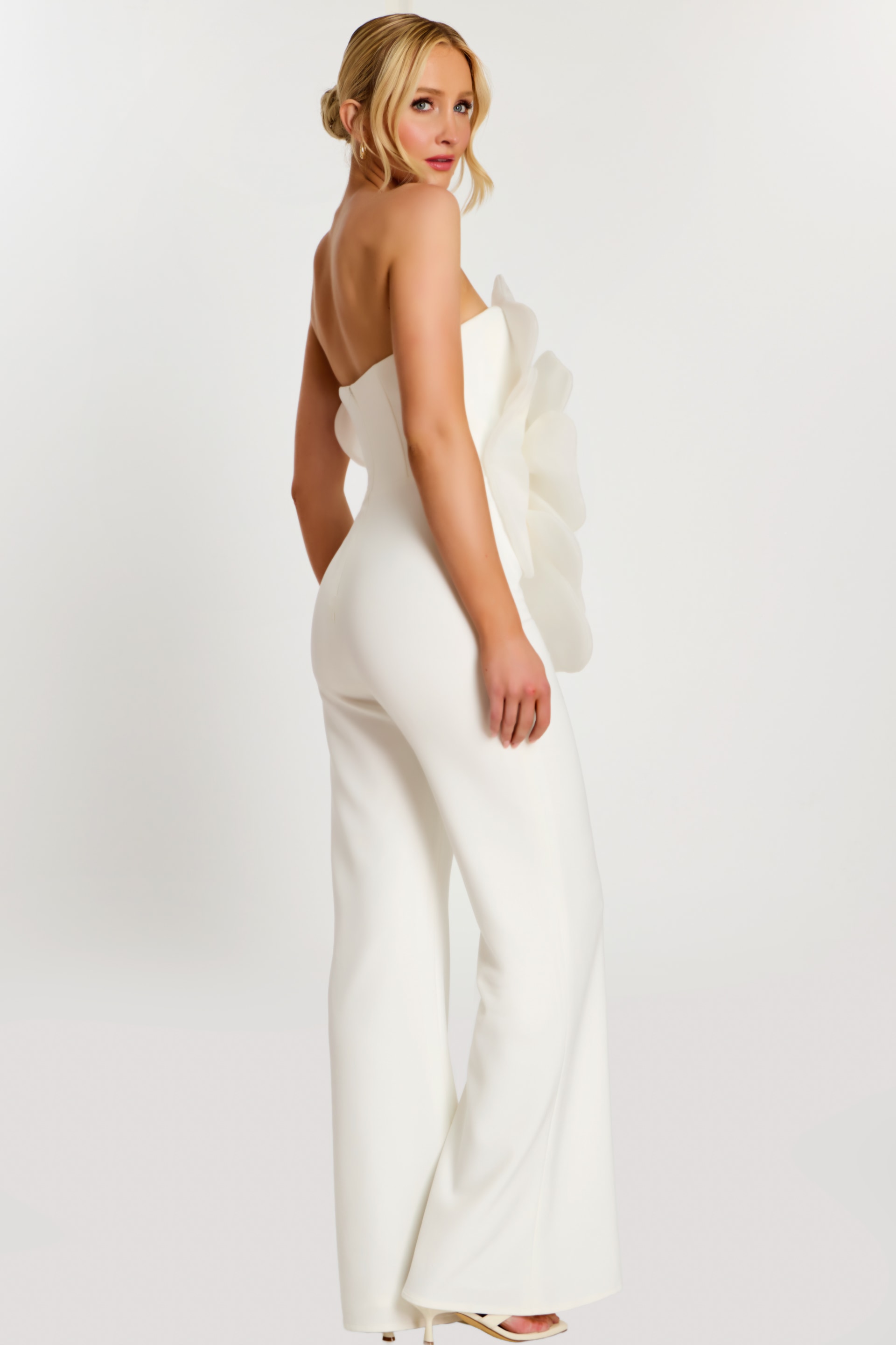 Over-the-shoulder pose showing back and side of white floral jumpsuit