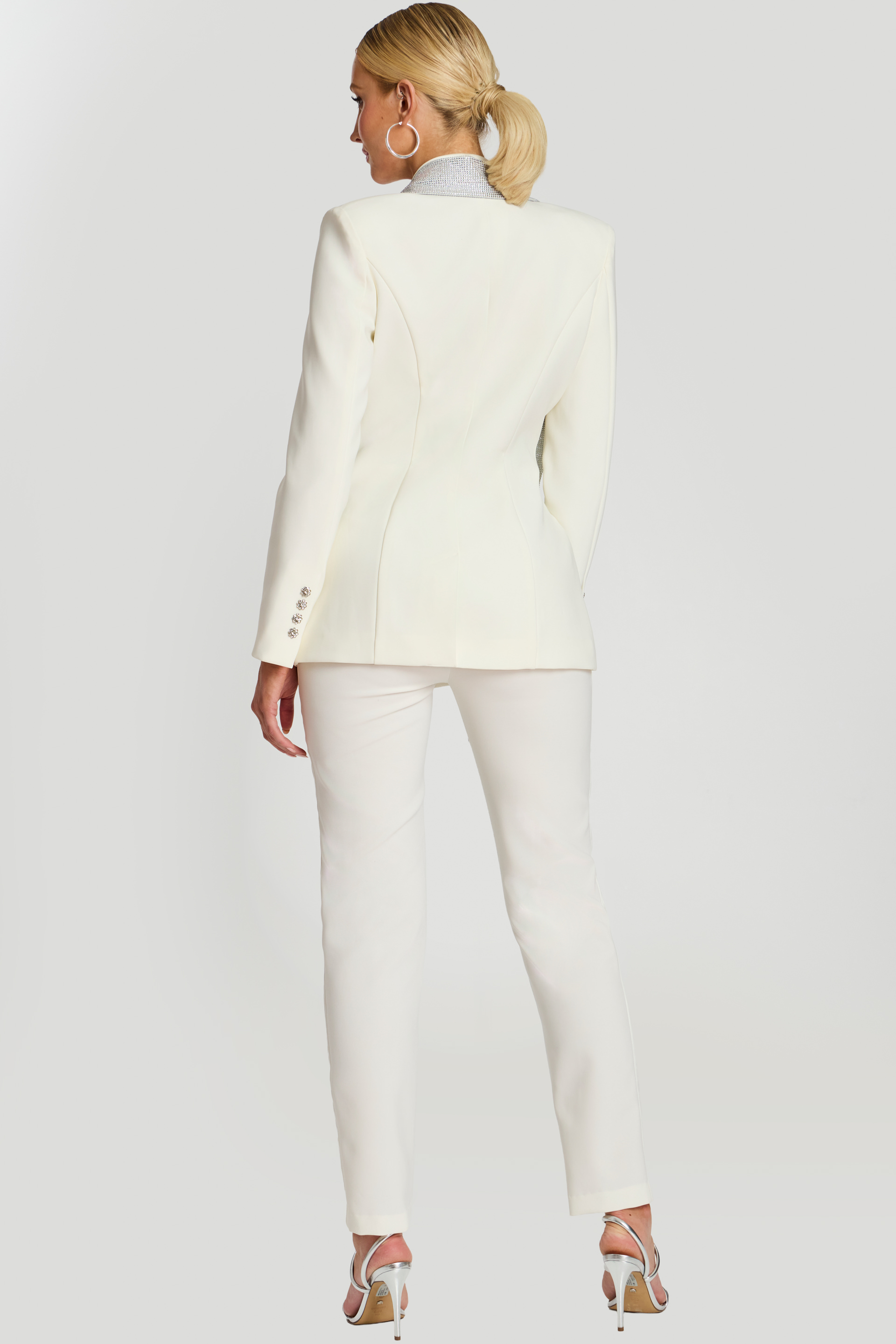 Back view of fitted white suit with structured seams and rhinestone collar