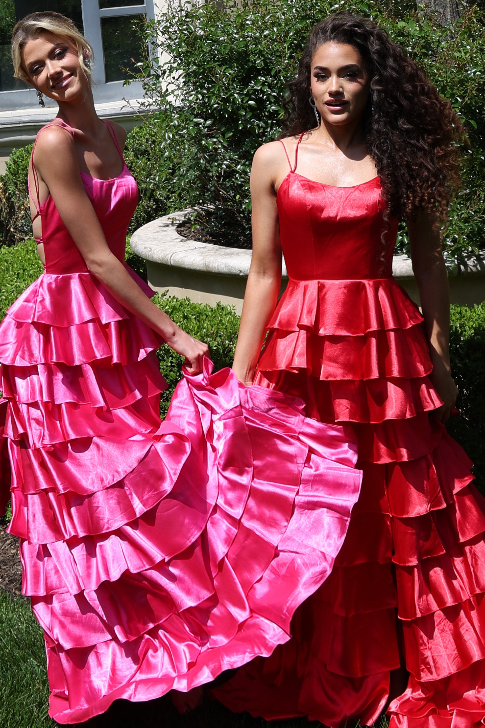 tiered satin dress with spaghetti straps - two girls front, hot pink red dresses holding skirts