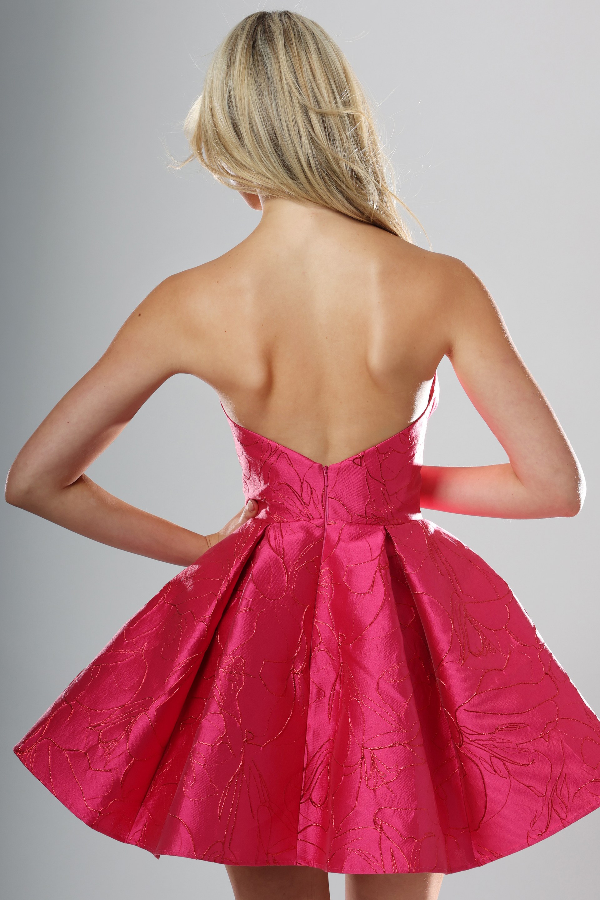 back view of raspberry brocade strapless A-line short homecoming dress with sweetheart bow neckline and pleated skirt, Jovani style 52120