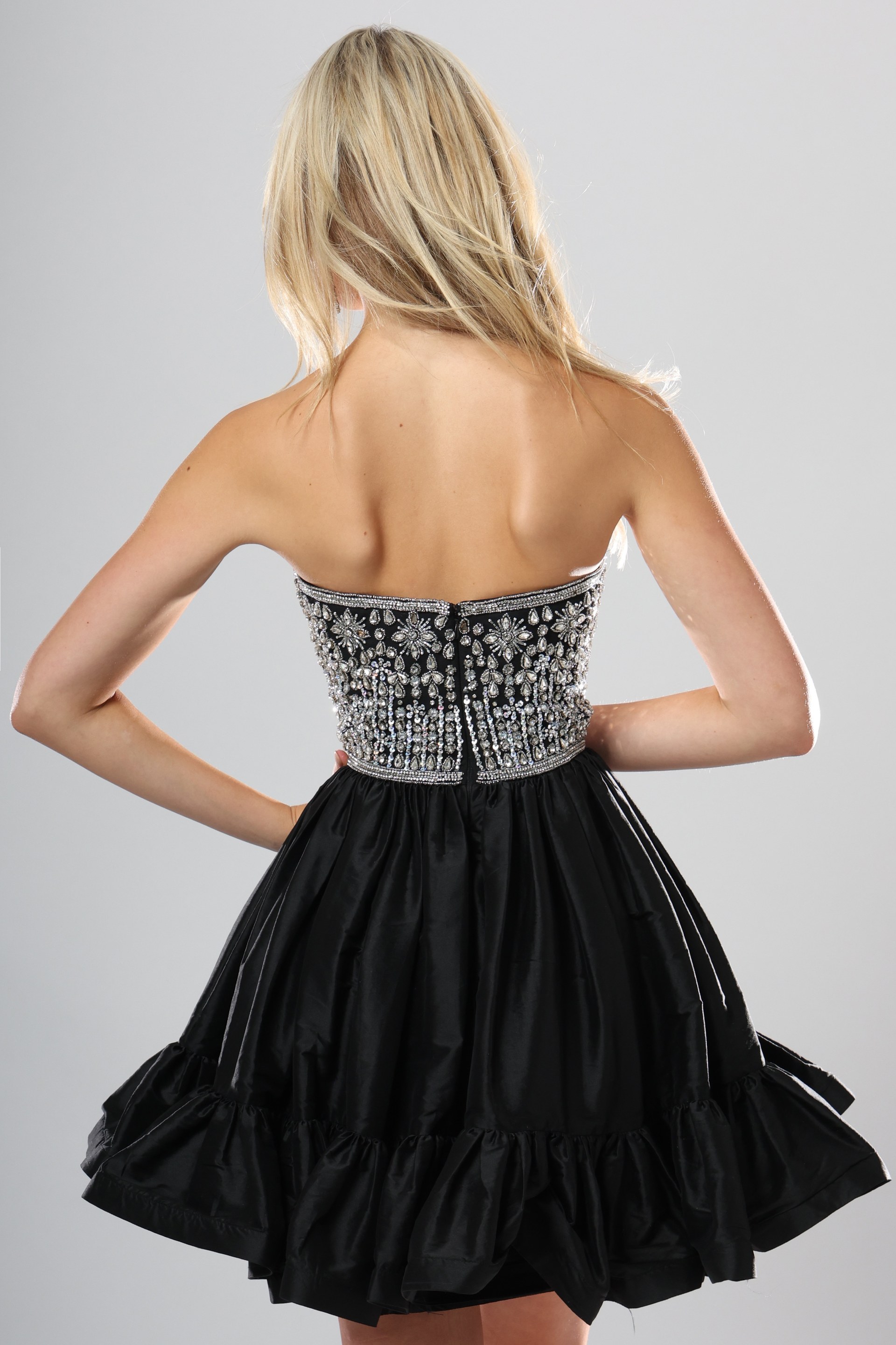 back view of black and silver beaded corset short homecoming dress with straight neckline and tiered ruffle skirt, Jovani style 52439