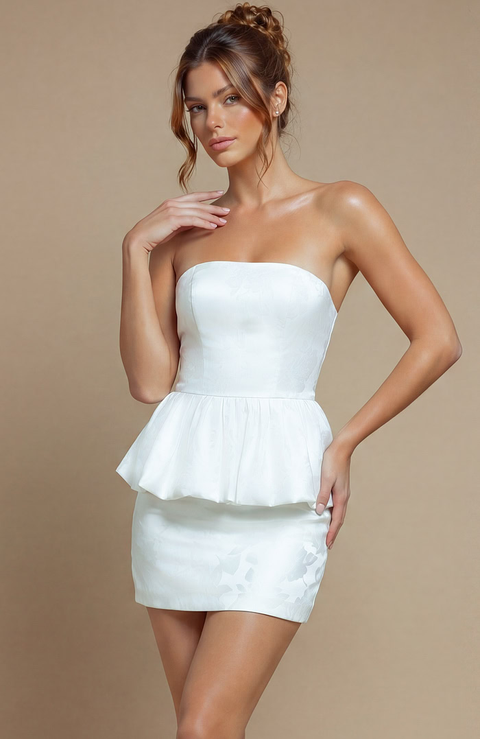 White evening dress featuring a reinforced bodice for a tailored fit and a sculptural, ruffled peplum hemline.
