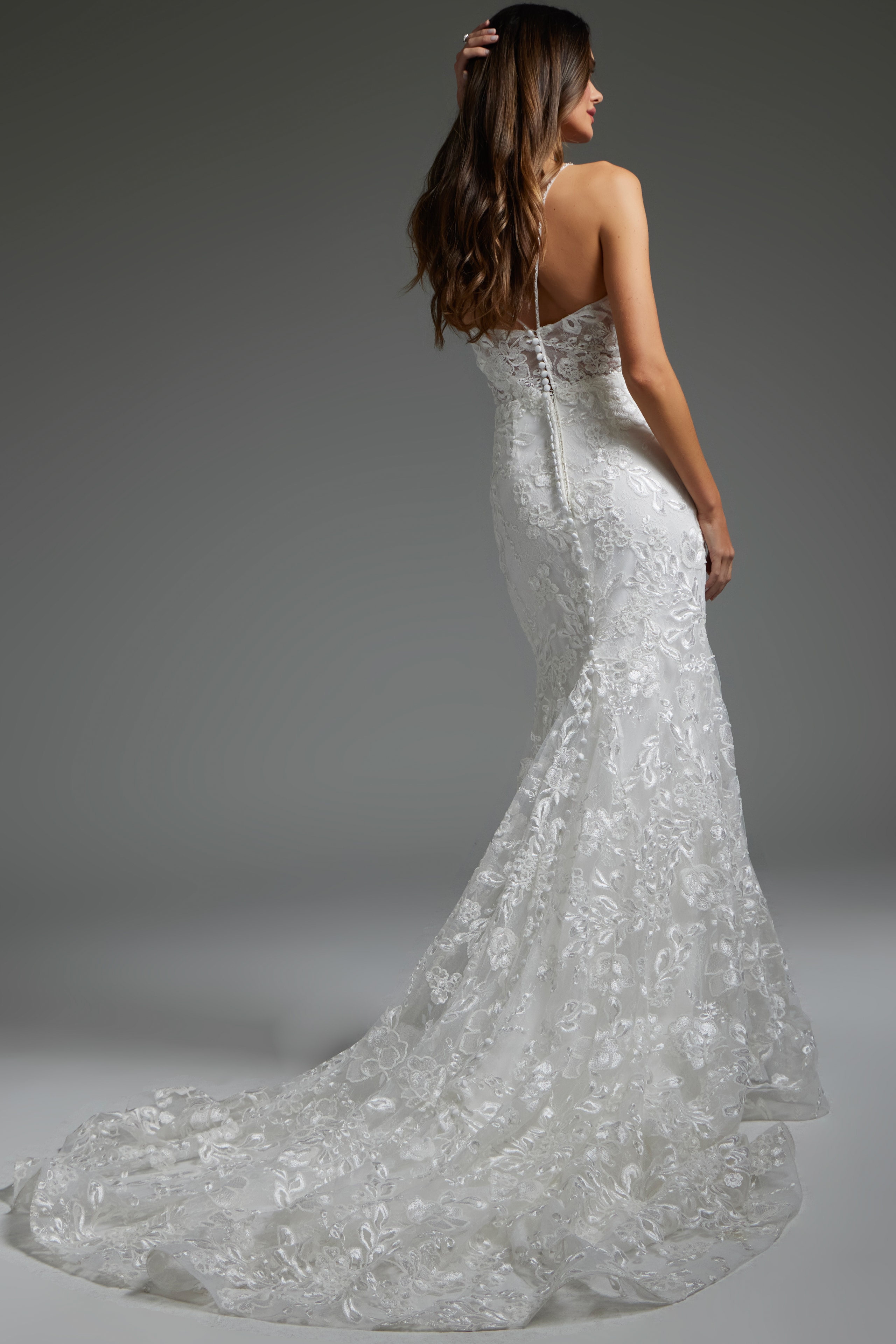 Model wearing Jovani JB37538 white gown, back view, showing off the seamless finish and elegant button detailing.
