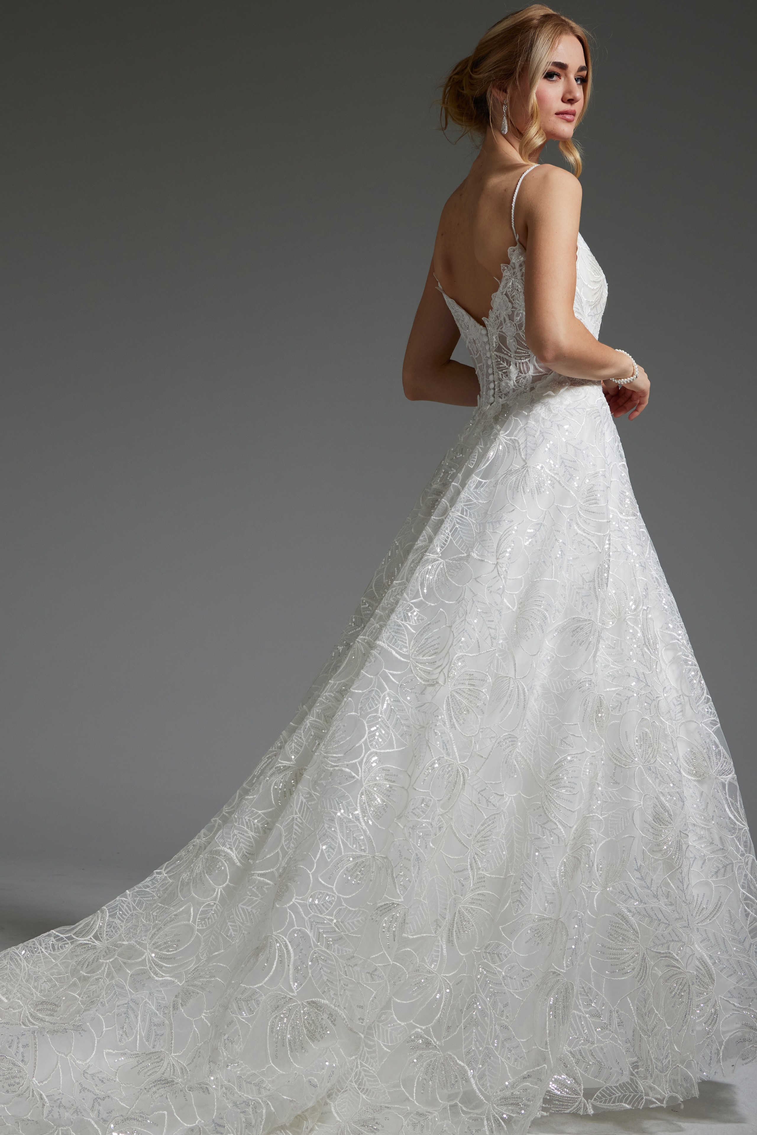 Model showcasing the back of Jovani JB422225 ivory gown with V-cut design.