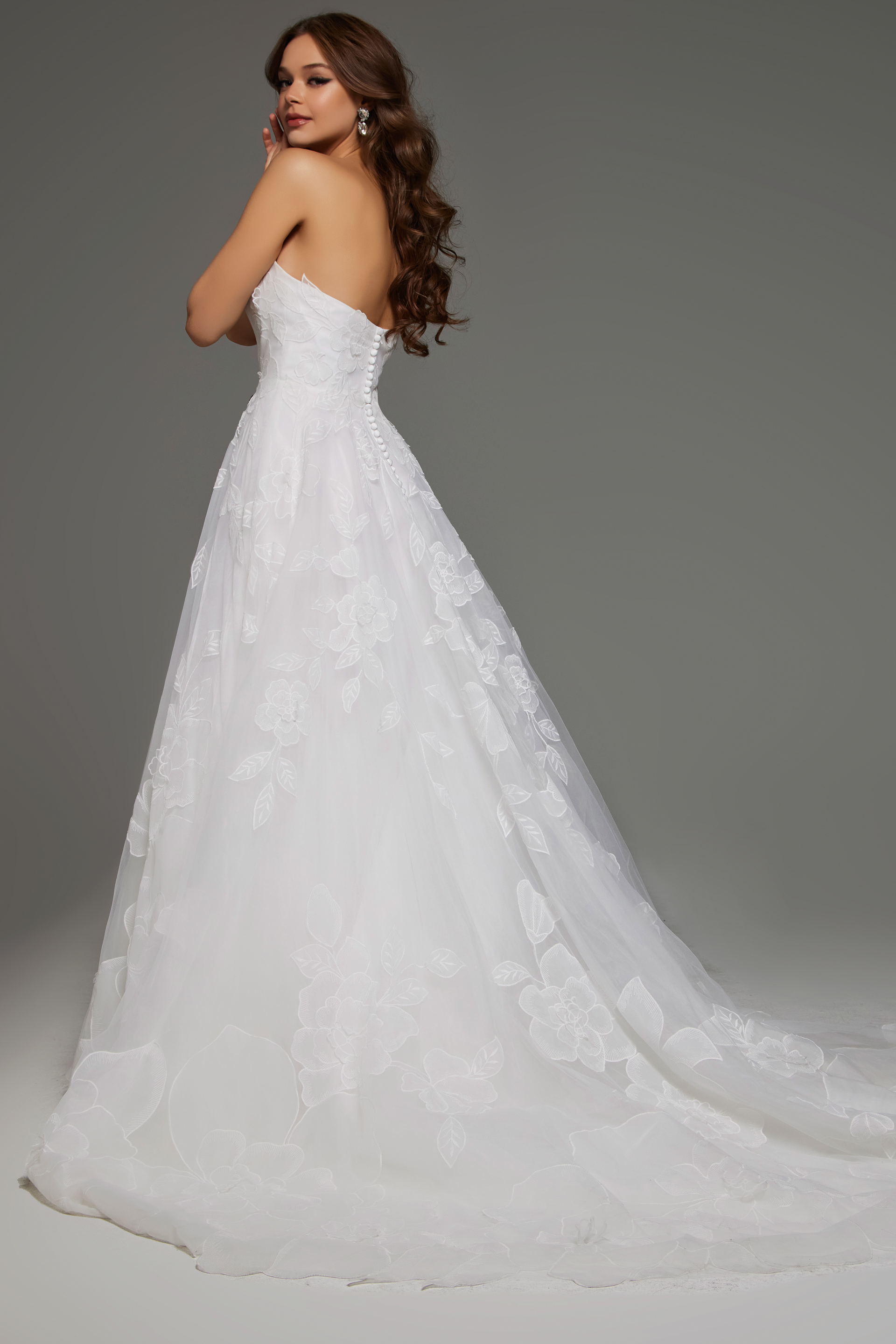 Back view of model in Jovani JB42324 showing button details and floral applique on ivory fabric.