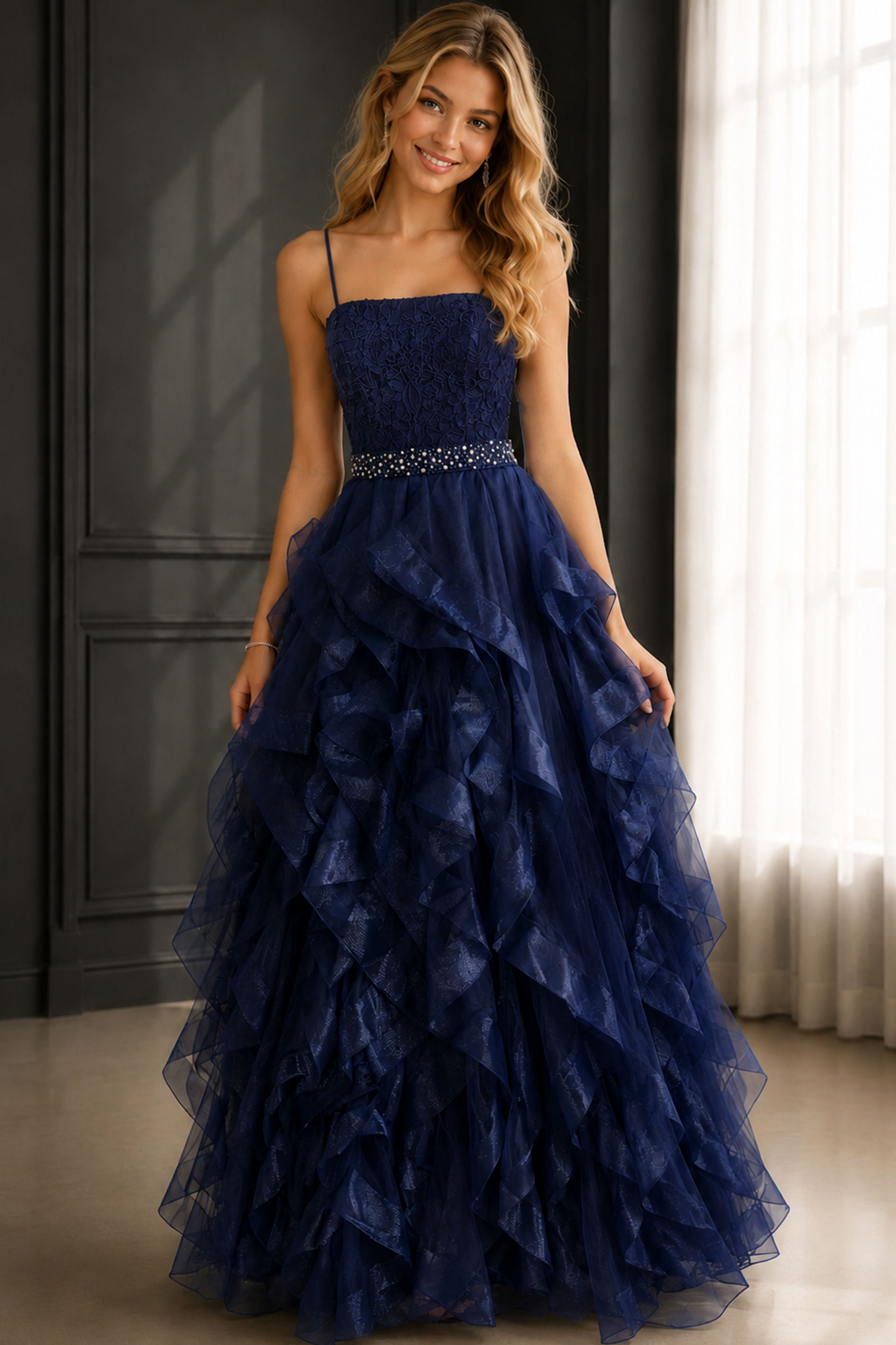 Navy ball gown with lace bodice, spaghetti straps, ruffled tulle skirt, and jeweled waist.