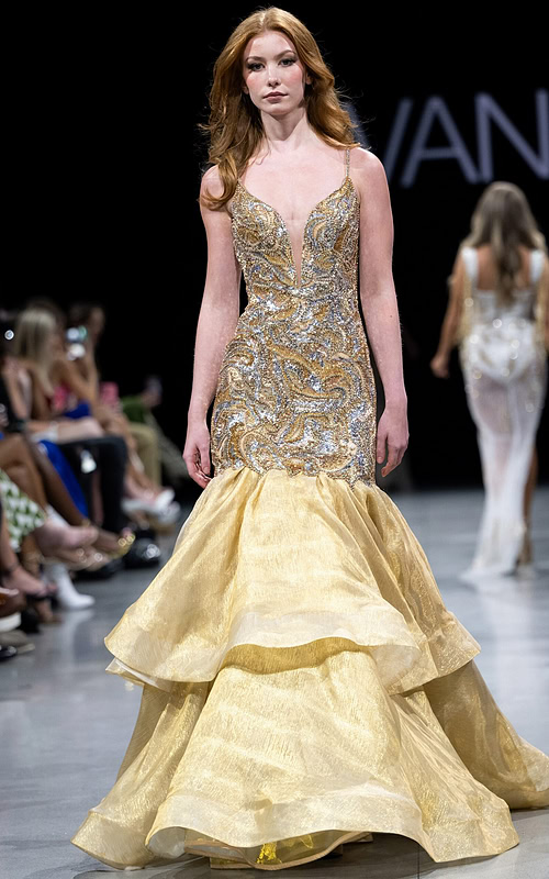 Model wearing Jovani S38449 gold mermaid gown with a plunging V-neckline and layered skirt